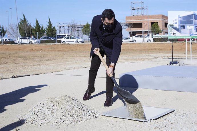 El presidente de la Junta, Juanma Moreno, echa una palada de arena en el hueco donde se encuentra la primera piedra durante la puesta de la primera piedra del Instituto de FP Aeroespacial en San José de la Rinconada
