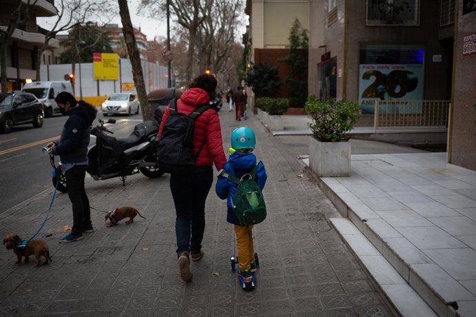 Una dona porta un nen a classe