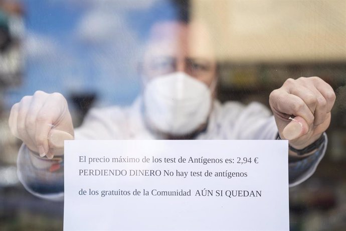 Un farmacéutico coloca un cartel, que indica que pierden dinero con el nuevo precio de los test, en una farmacia en Carabanchel, a 13 de enero de 2022, en Madrid (España). 