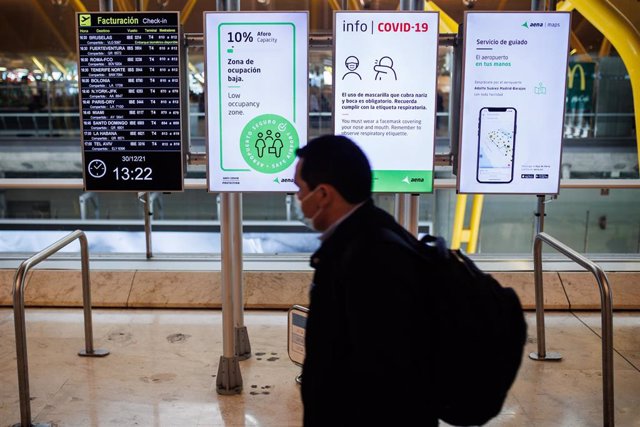 Una persona pasa delante de unos paneles con las medidas de seguridad Covid en la Terminal 4 del Aeropuerto Adolfo Suárez-Madrid Barajas, a 30 de diciembre de 2021, en Madrid, (España).
