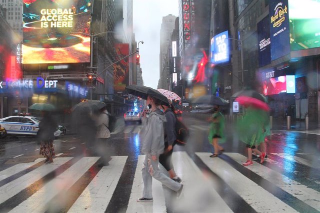 Archivo -  US, New York: Pedestrians protect themselves from heavy rain with umbrellas as they cross a street at Times Square