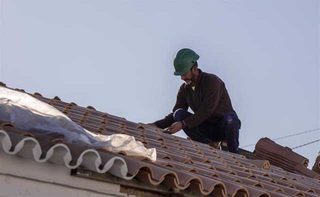 Archivo - Un obrero realiza su labor en el tejado de una vivienda, en foto de archivo.