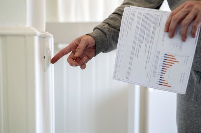 Un home encén un interruptor amb una factura de llum a la m, a 3 de gener de 2022, a Madrid, (Espanya). 