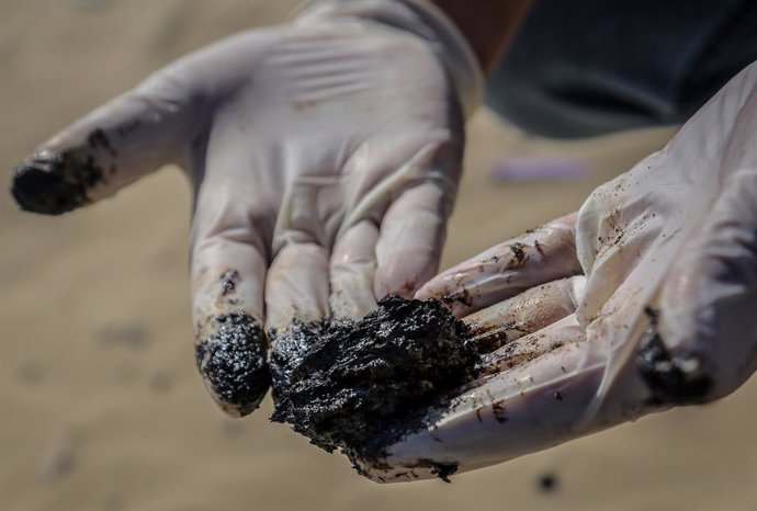 Archivo - 27 February 2021, Lebanon, Tyre: A Lebanese volunteer holds tar during a cleaning campaign of beaches at the city of Tyre, after an oil spill deposited tar over large stretches of the coast in the southern part of Lebanon. Tar from an offshore