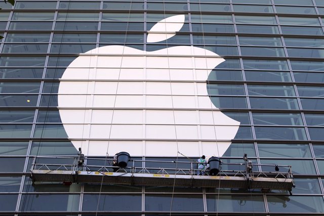 Archivo - FILED - 11 June 2016, US, San Francisco: Workers affix an oversized Apple logo to a glass facade. Apple on Wednesday became the first publicly traded company from the United States to hit a market capitalization of 2 trillion dollars, doubling i