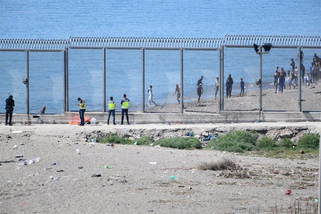 Archivo - Varios policías vigilan desde la valla que separa Ceuta de Marruecos la llegada de migrantes, el 19 de mayo de 2021