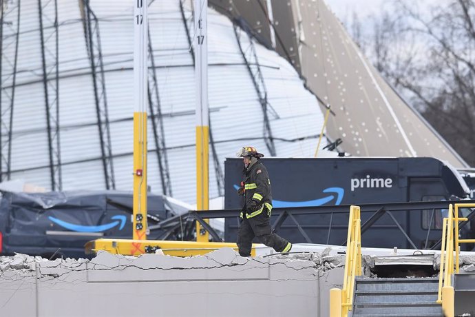 Empleado del servicio de emergencias de Estados Unidos frente a un almacén de Amazon colapsado a causa de un tornado en el estado de Illinois