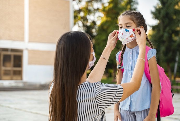 Archivo - Madre ajustando la mascarilla. Mascarilla tela, niña, cole, escuela, colegio clases. Niña, covid.