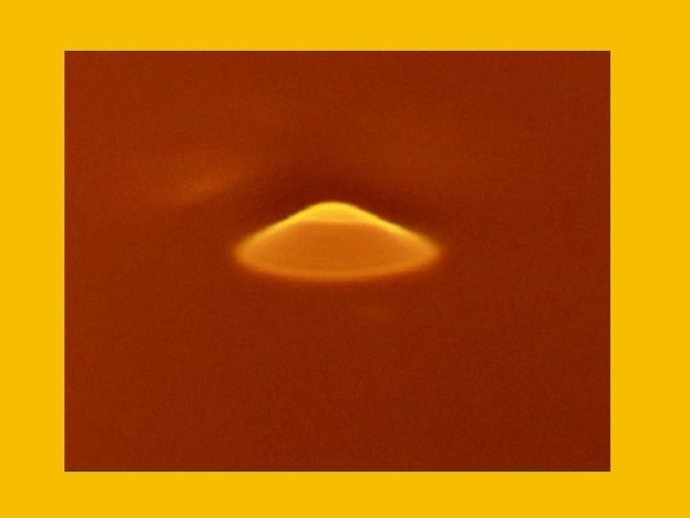 Una fuente inducida por láser, en amarillo, es creada por un rayo láser que brilla en la superficie de ferrofluido en el laboratorio de Bao.