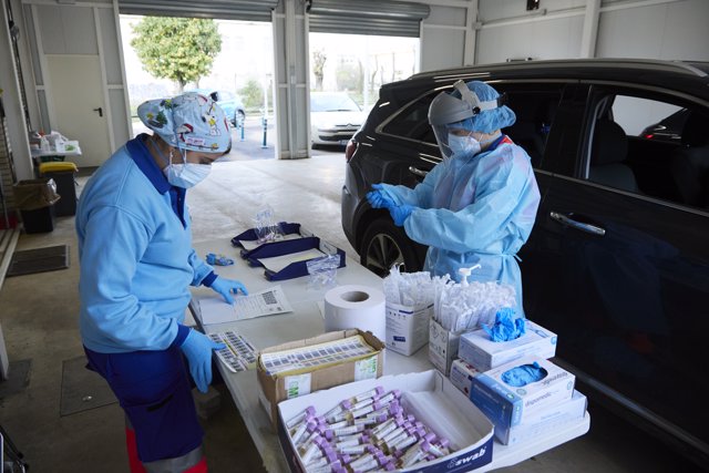 Dos enfermeras preparan el test en una mesa durante la realización de PCR en el autocovid instalado en el Hospital Militar, a 28 de diciembre de 2021 en Sevilla (Andalucía, España)