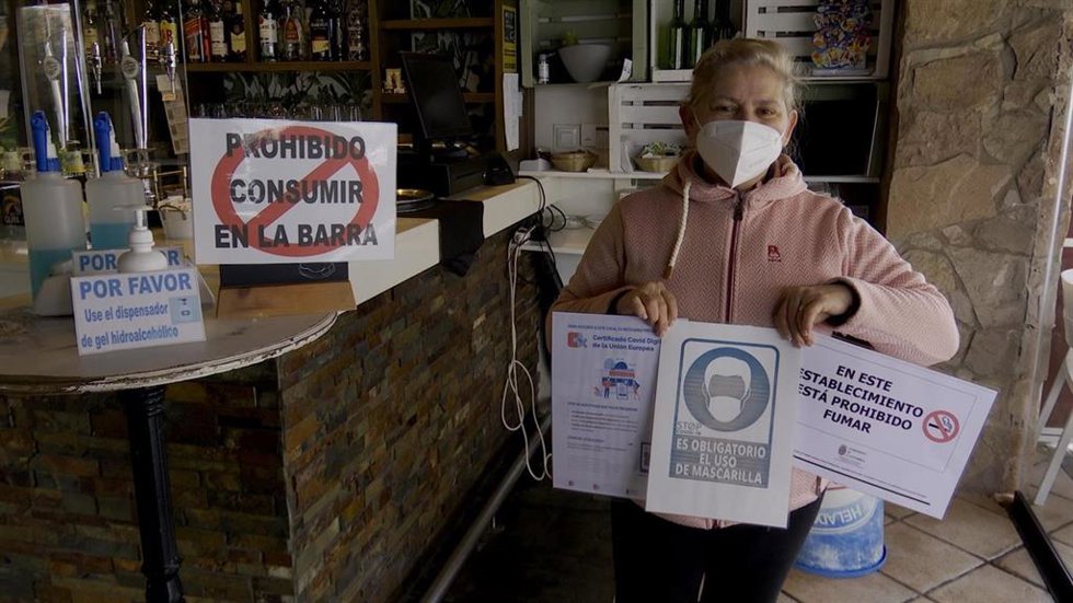Una hostelera sostiene carteles de prohibiciones en los establecimientos