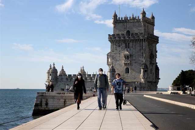 Personas con mascarilla pasean junto al río Tajo en Lisboa