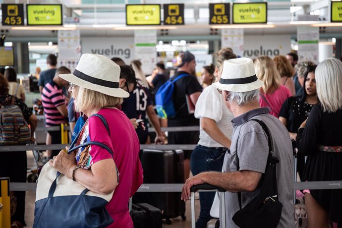 Archivo - Diferentes viajeros esperan en el puesto de Check-In de la compañía Vueling en el Aeropuerto 'Josep Tarradellas Barcelona-El Prat'.