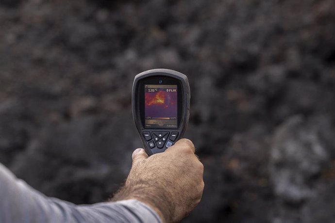 Archivo - Un hombre mide la temperatura de una colada de lava, en la zona de exclusión próxima al volcán de Cumbre Vieja