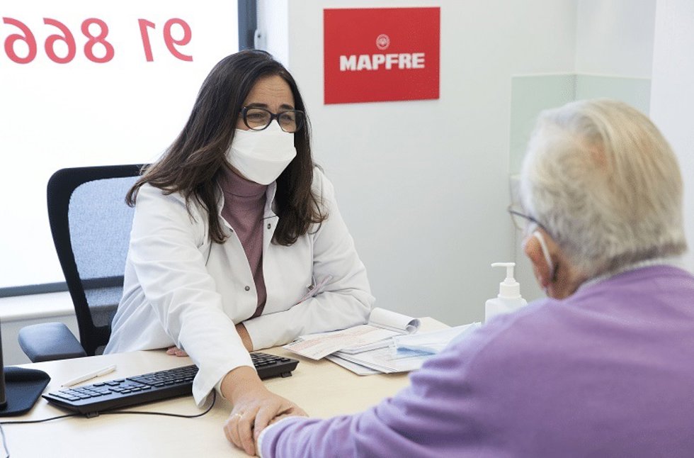 Archivo - Una empleada de Mapfre atiende a un cliente sénior.