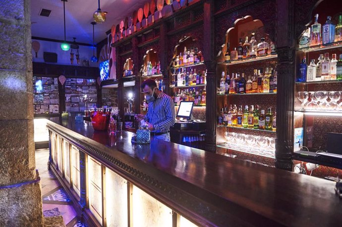 Un trabajador prepara una copa en la barra de un bar 