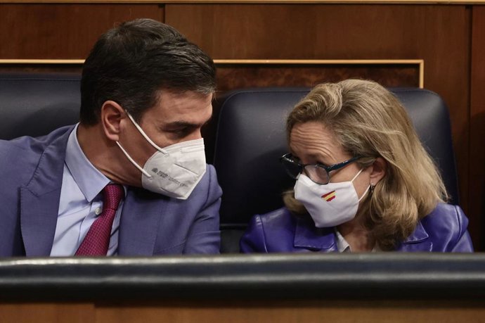 El presidente del Gobierno, Pedro Sánchez, y la vicepresidenta primera del Gobierno y ministra de Asuntos Económicos y Transformación Digital, Nadia Calviño, conversan en una sesión plenaria en el Congreso de los Diputados, a 28 de diciembre de 2021, en
