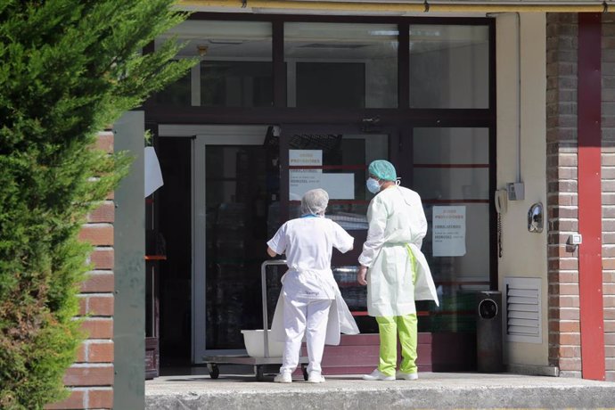 Archivo - Dos trabajadores a las puertas de una residencia en Lugo.