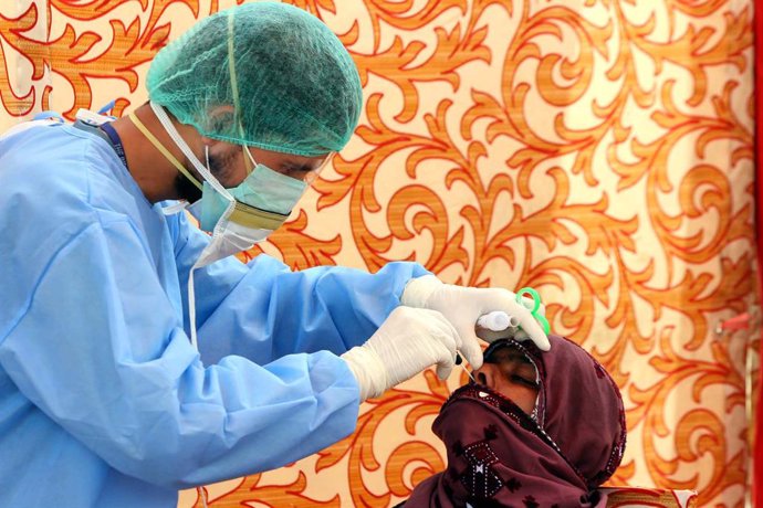 Archivo - Un trabajador sanitario hace una prueba por coronavirus a una paciente en Pakistán durante la pandemia