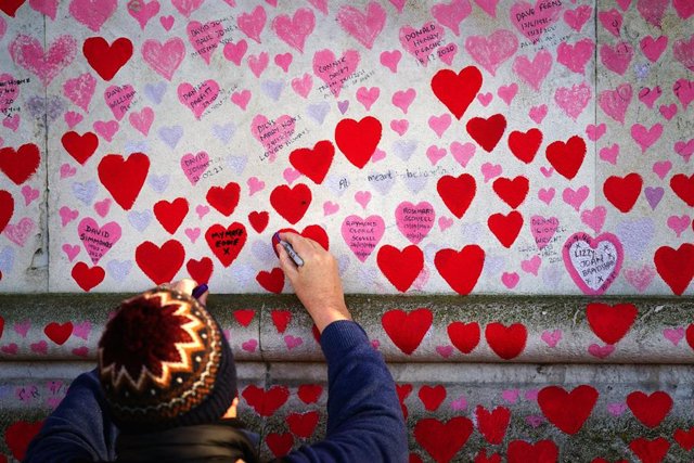 Un hombre escribe en el memorial por las víctimas de la COVID-19 en Londres, la capital de Reino Unido. 