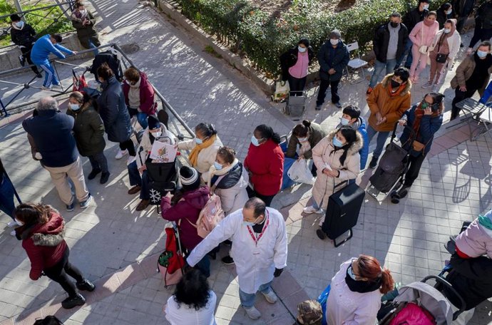 Varias personas hacen cola para recibir alimentos.
