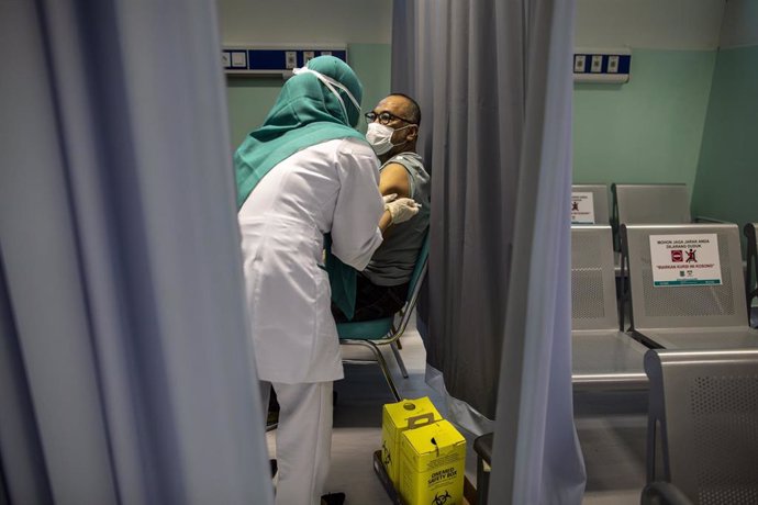 24 January 2022, Indonesia, Tangerang Selatan: A man receives a coronavirus vaccine booster shot at the South Tangerang Hospital.