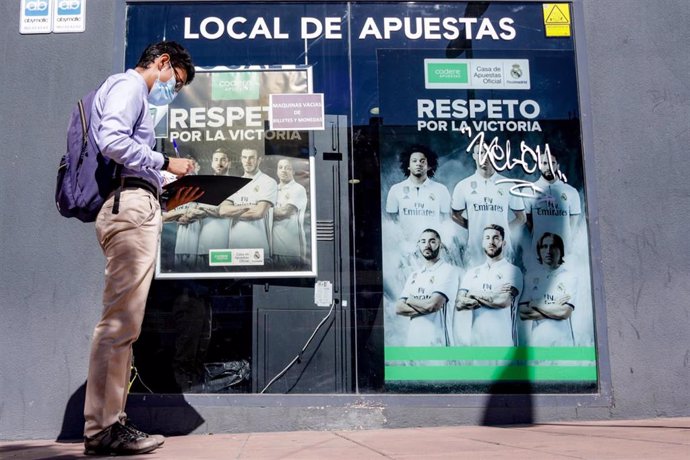 Archivo - Un hombre pasa por un local de apuestas.