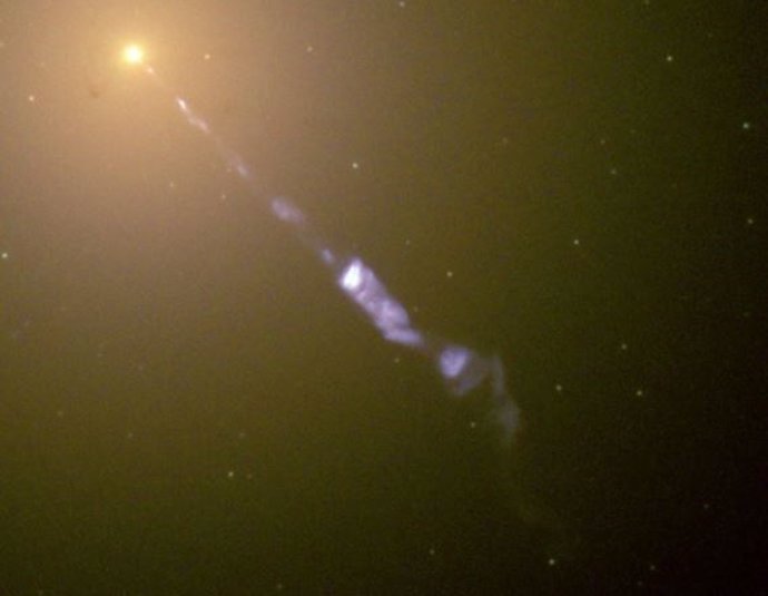 Chorro de electrones y partículas subatómicas impulsado por un agujero negro que se transmite desde el centro de la galaxia M87; la luz azul es radiación de sincrotrón que debería producir una reacción de radiación.