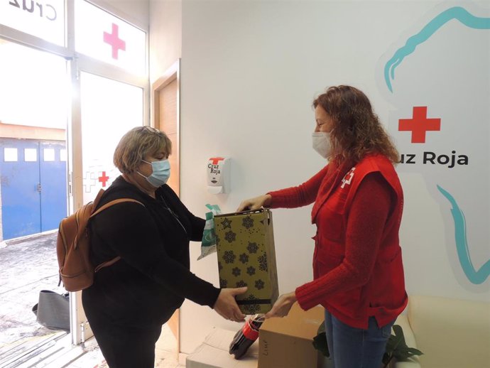 Una trabajadora de Cruz Roja entrega un lote de Navidad a una afectada por el volcán de La Palma