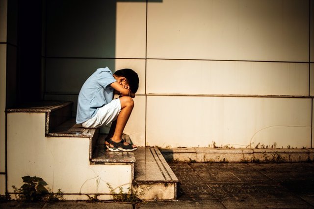 Archivo - Niño sentado en una escalera, triste, deprimido.