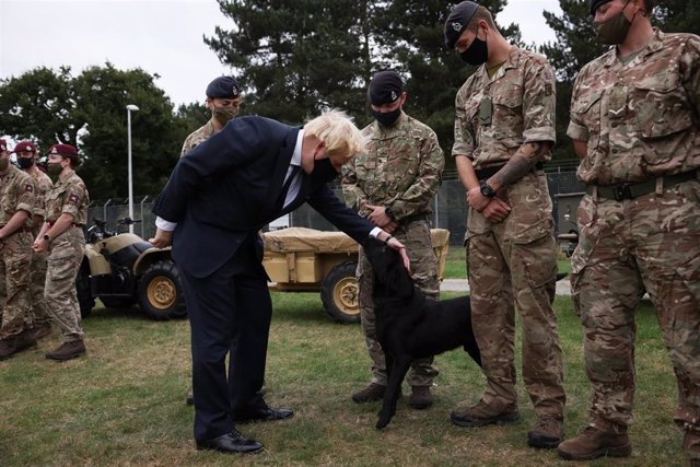 Boris Johnson junto a un grupo de militares y un perro.