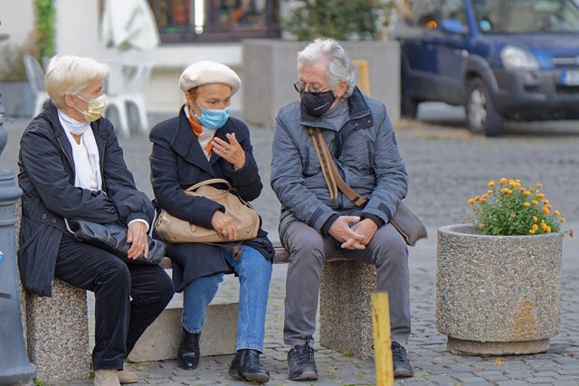 Personas mayores sentadas en un banco en la calle
