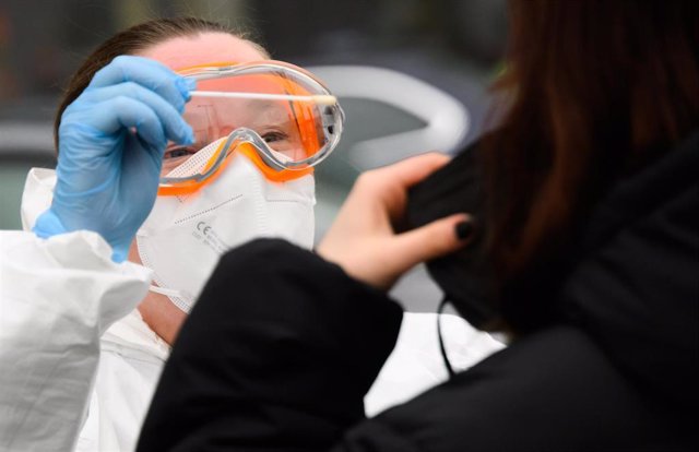 26 January 2022, Lower Saxony, Laatzen: A family doctor takes a swab sample from a person to perform PCR test coronavirus outside a doctor's office in the Hannover region. Photo: Julian Stratenschulte/dpa