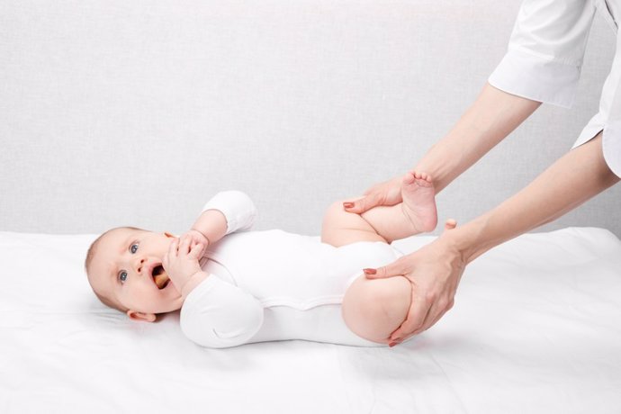 Archivo - Bebé pequeño recibiendo tratamiento en su pierna para prevenir la displasia de cadera por fisioterapeuta pediátrico.