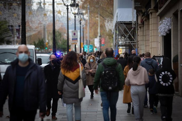 Archivo - Viandantes caminan con bolsas por una vía de Barcelona, a 27 de diciembre de 2021, en Barcelona, Catalunya, (España).  
