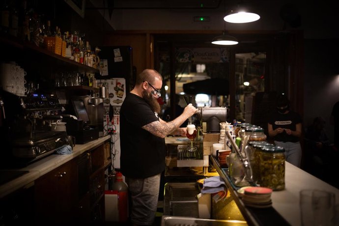 Archivo - Arxiu - Un cambrer serveix una cervesa a l'interior d'un bar en un carrer cntric de Barcelona.