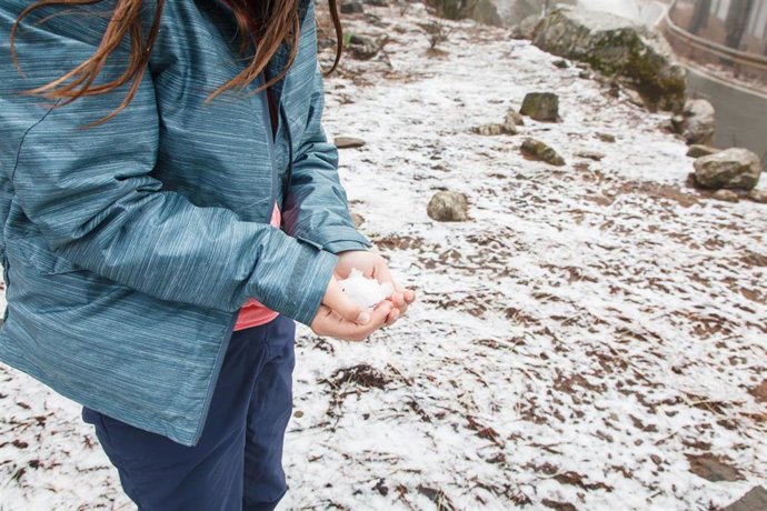 Archivo - Una mujer coge una bola de nieve en la cumbre de Gran Canaria que ha amanecido con un fino manto de nieve con motivo de la llegada de un temporal a la isla, Las Palmas de Gran Canaria, Canarias, (España), a 5 de febrero de 2021. El temporal, u