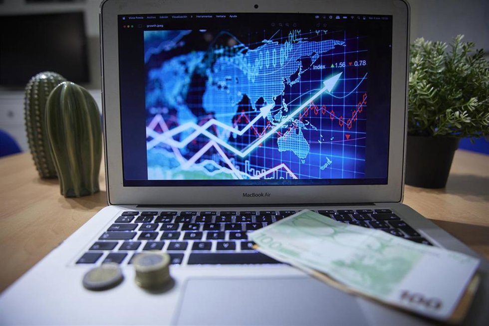 Un gráfico en un ordenador portátil con billetes y monedas, a 4 de enero de 2022, en Madrid, (España).