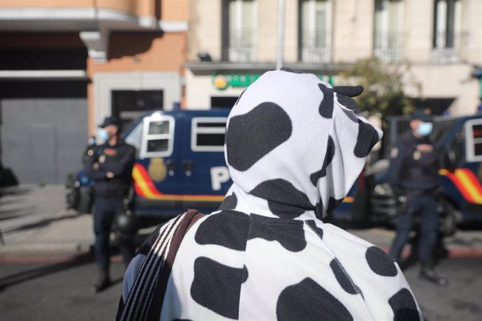 Una manifestante vestida de vaca, durante la protesta frente a varios agentes de la Policía Nacional