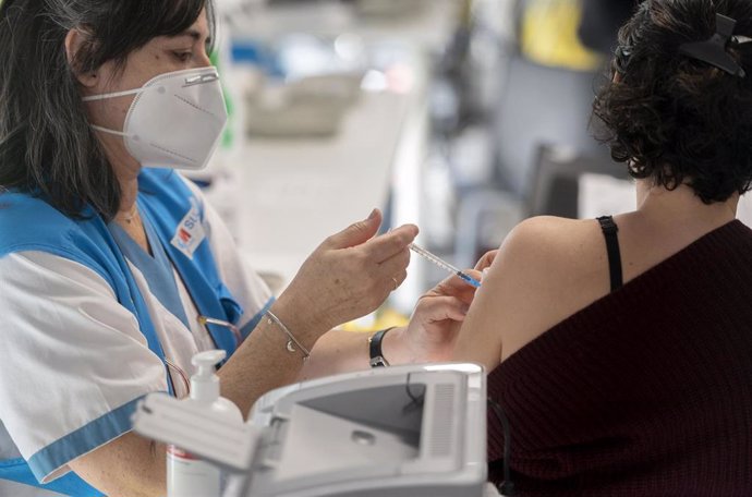 Una mujer recibe la tercera dosis de la vacuna contra el Covid-19, en el WiZink Center, a 20 de enero de 2022, en Madrid, (España). Hoy arranca, en la red de hospitales públicos de la Comunidad de Madrid  la inoculación de la tercera dosis de la vacuna 