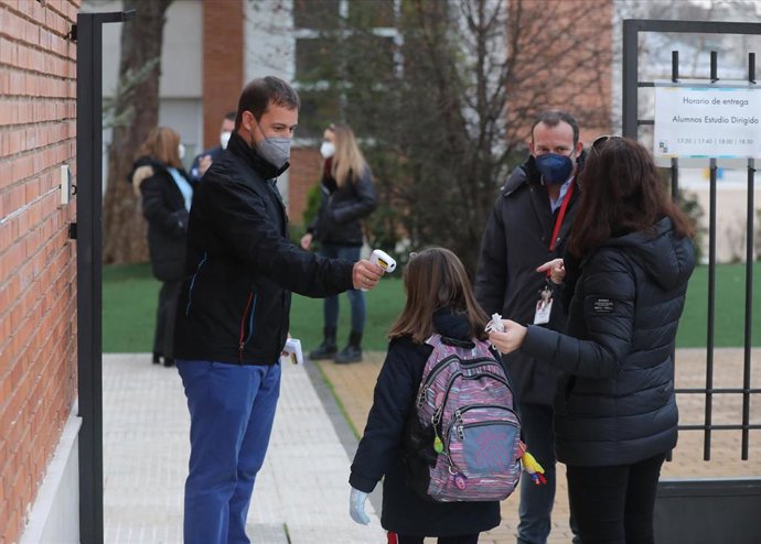Un trabajador toma la temperatura a un niño a su llegada al primer día de clase presencial tras la Navidad 