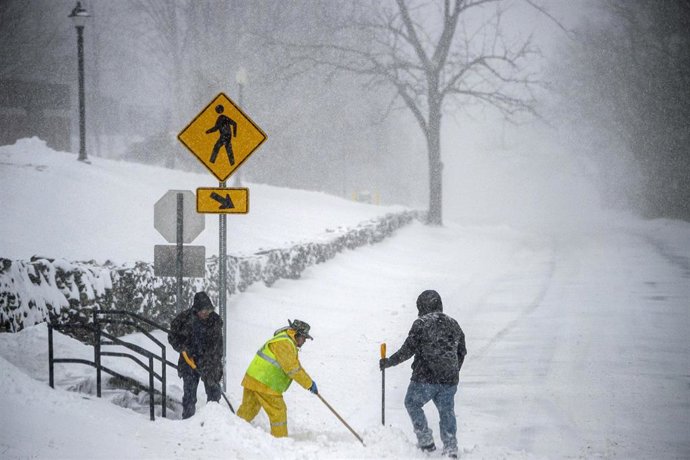 Un equipo limpia de nieve una escalera y un paso de peatones el sábado 29 de enero de 2022, en Mansfield, Connecticut.