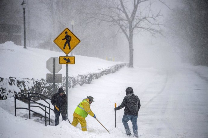 Un equipo limpia de nieve una escalera y un paso de peatones el sábado 29 de enero de 2022, en Mansfield, Connecticut.