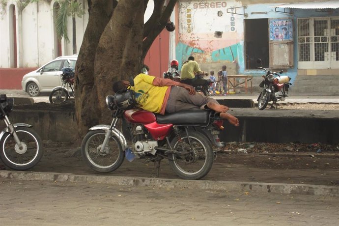 Archivo - Hombre durmiendo sobre su moto en Cotonou, Benín, África