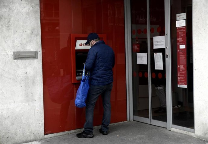 Archivo - Un hombre saca dinero de un cajero del Banco Santander un día después de que Banco Central Europeo (BCE) haya especificado que decidirá "banco a banco" la hoja de ruta para recuperar los niveles de capital y liquidez previos a la crisis genera