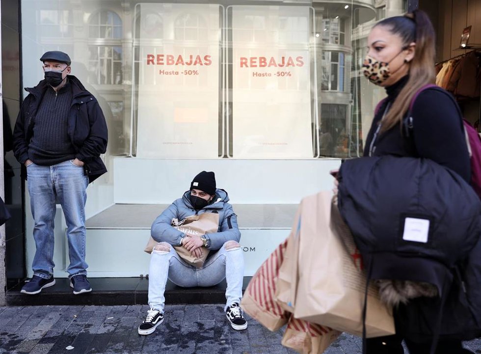 Varias personas delante del escaparate de una tienda con descuentos de hasta el 50%, a 7 de enero de 2022, en Madrid (España). 