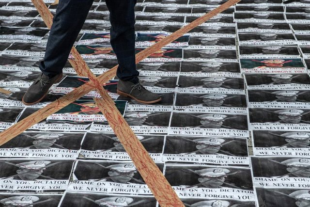 Archivo - Un hombre pisa carteles con la cara del jefe del Ejército de Birmania, Min Aung Hlaing.