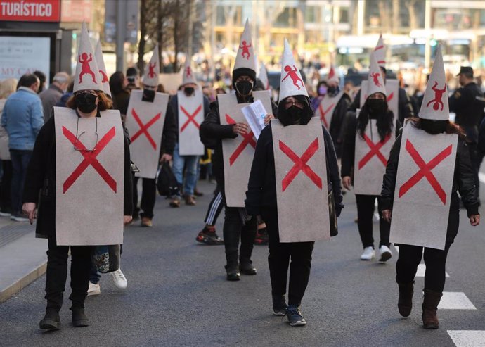 Varios manifestantes vestidos con petos tachados con cruces y capirotes blancos con niños dibujados, durante la manifestación en defensa de los menores tutelados, en el centro de Madrid a 29 de enero de 2022, en Madrid (España). 