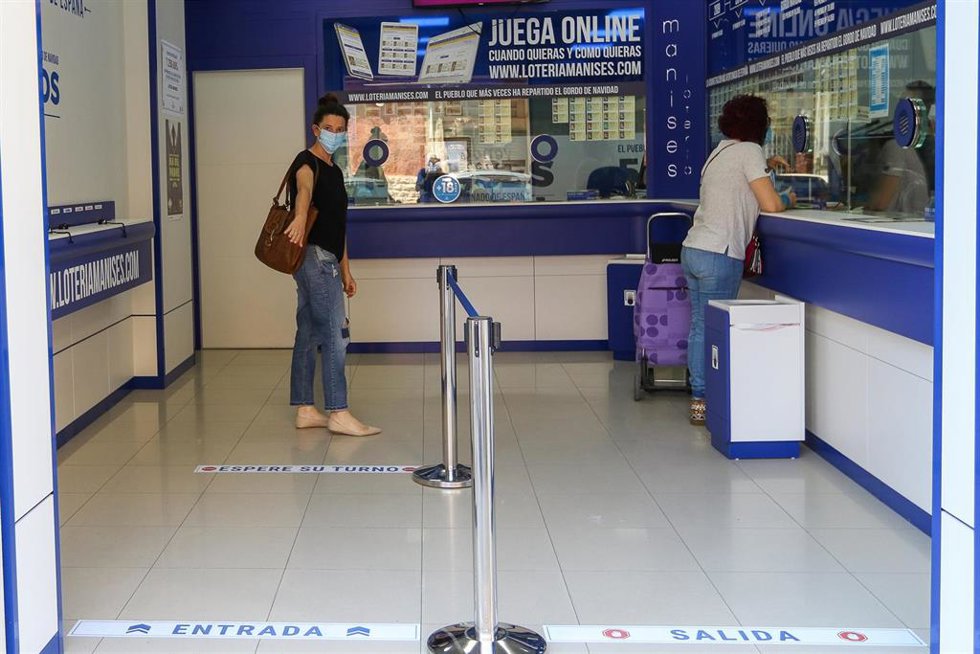 Archivo - Una mujer compra lotería en una Administración en una imagen de archivo.