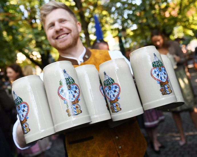 Archivo - 18 September 2021, Bavaria, Munich: A man holds special mugs at the Viktualienmarkt during the start of the "WirtshausWiesn 2021". Despite Munich's traditional Oktoberfest beer festival being cancelled for the second year in a row due to the c